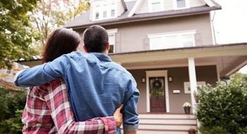 A couple hugging and looking at their house